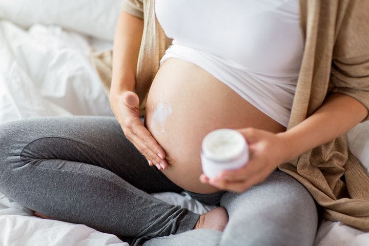Woman applying cream to her pregnant belly