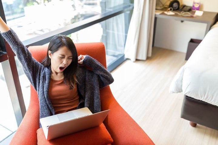 Woman yawning while working on her laptop 