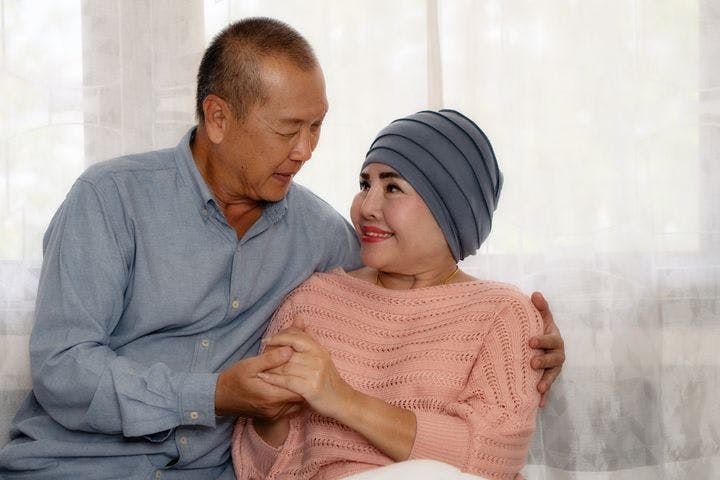 Elderly Asian couple encouraging each other as the wife is on cancer treatment.