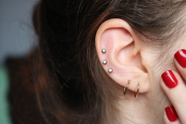 Closeup of a woman’s right ear with piercings.
