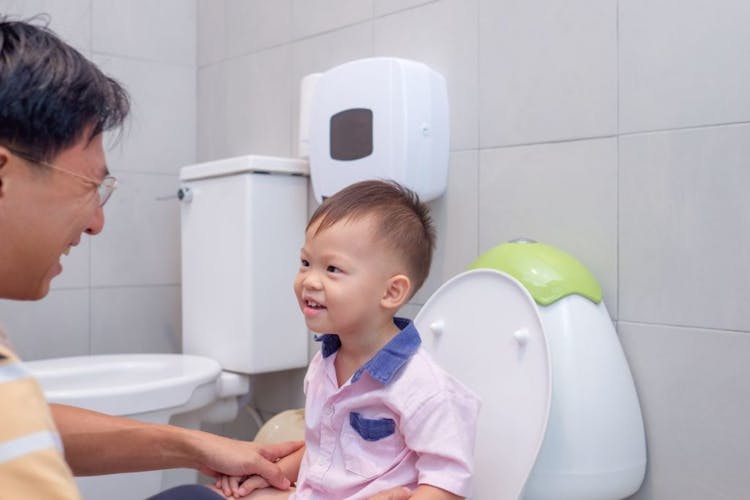 A father potty training his young son in the toilet