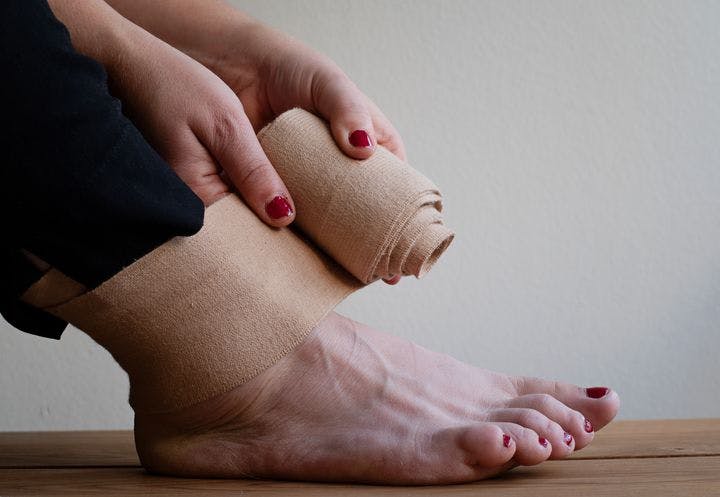 Woman wraps an elastic bandage around her right ankle