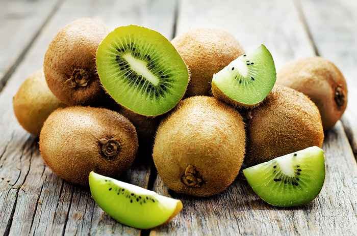 Kiwifruit in halves and slices on a wooden table.