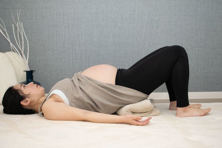 Pregnant woman lying on her back with her hips in the air.