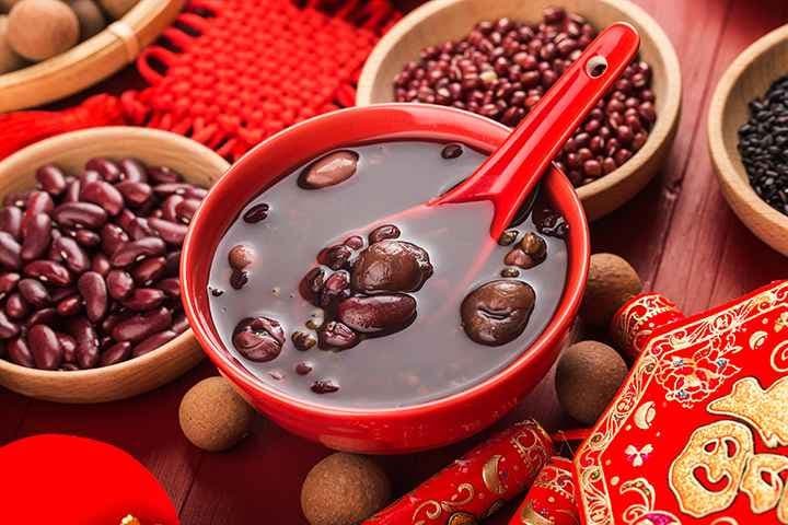 'Eight Treasures' Soup displayed in a red bowl alongside bowls of various ingredients