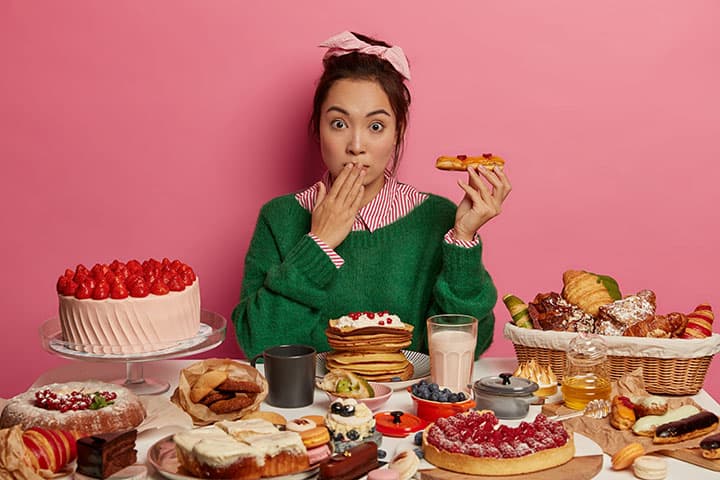 Woman surrounded by sweet, rich, and fatty foods