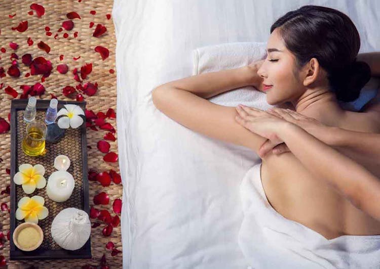 A woman getting a back massage as she lies on a white sheet 
