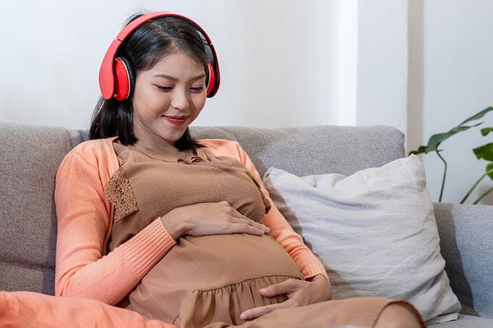A pregnant woman enjoying music through wireless headphones 