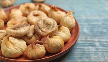 Dried figs on a wooden plate and on a wooden table
