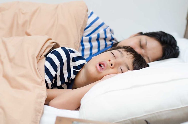 A boy and his mother fast asleep in bed