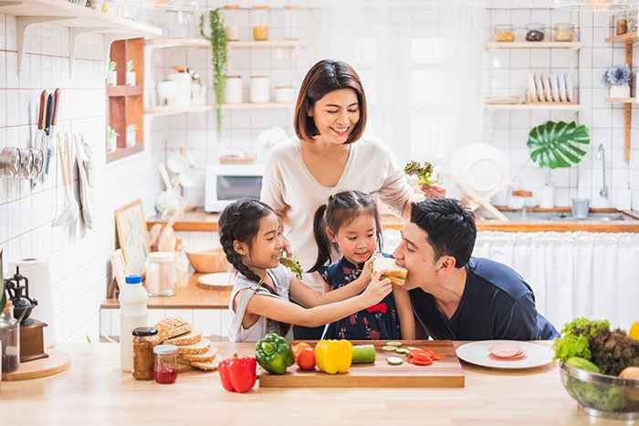 Asian family consists of parents and 2 daughters enjoy cooking together in the kitchen