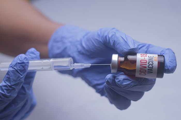 Close-up of a medical professional inserting a single dose of the COVID-19 vaccine into a syringe