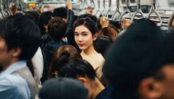 Young Asian woman standing in the middle of a packed train