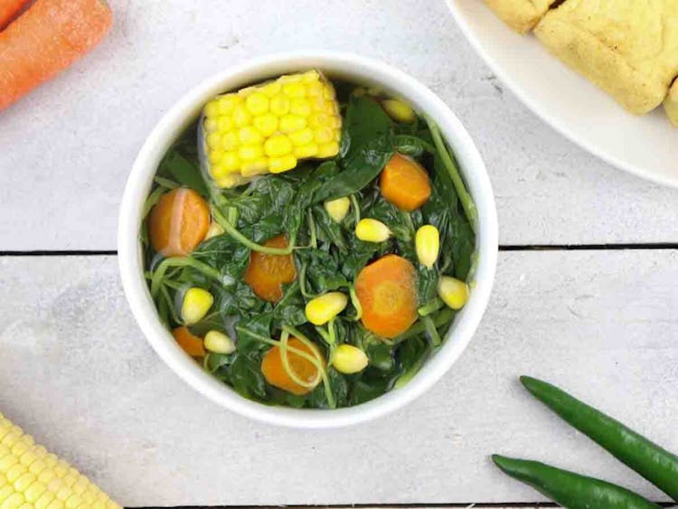 Spinach soup cooked with carrots and corn in a bowl