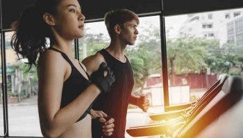 A man and woman running on treadmills inside a gym