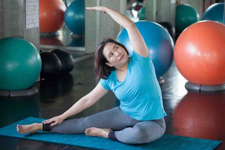An overweight woman doing a yoga exercise in a gym