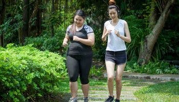 A slim woman and an overweight woman jogging at the park