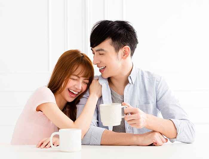 Happy Asian couple laughing while enjoying their drink