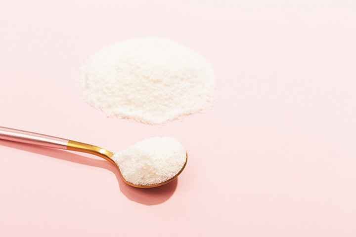 A spoon of white powder set on a pink background