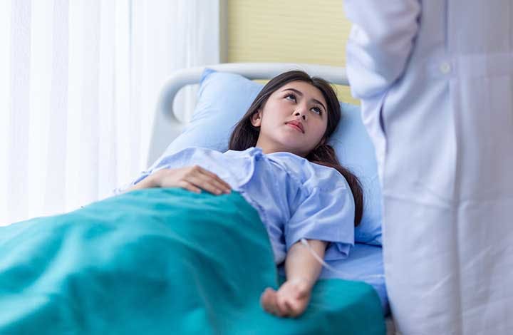 Asian woman with ectopic pregnancy is consoled by a doctor