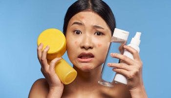 Woman frowning while holding skincare products 