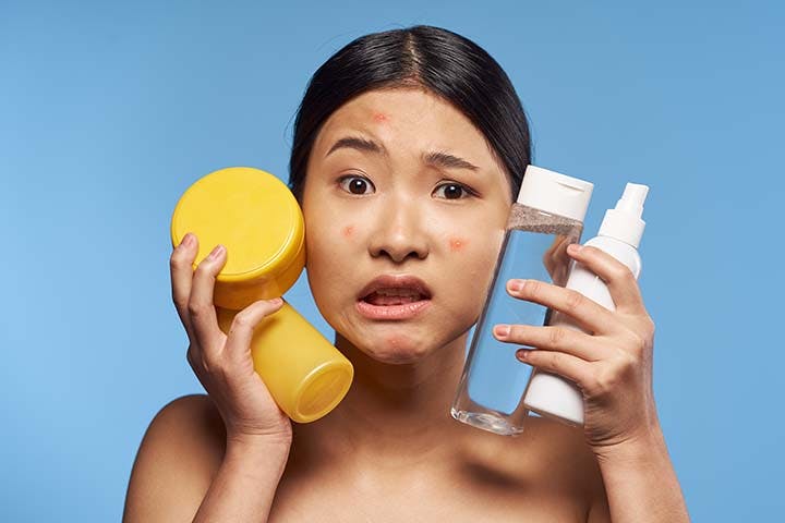 Woman frowning while holding skincare products 