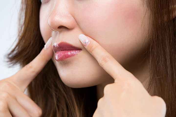Woman pointing to crease lines on her face using index fingers