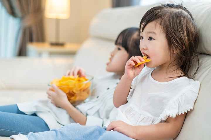 Little girl eating potato chips with older sister
