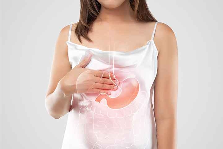 Stomach and oesophagus illustration superimposed over an image of a woman in a white dress touching the upper abdomen
