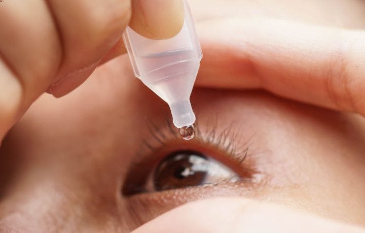 A patient using eye drops on her eye