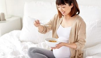 A pregnant woman eating a bowl of nutritious food 