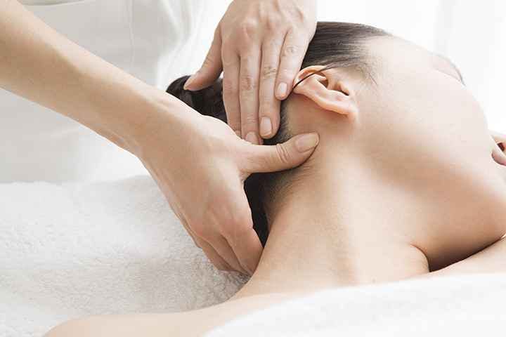 A close-up view of a woman receiving an acupressure massage on her neck muscles