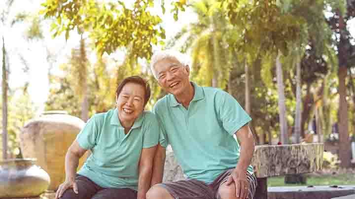 A happy elderly couple sitting together on a park bench