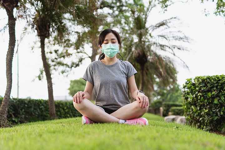 Asian woman with mask meditating in the open