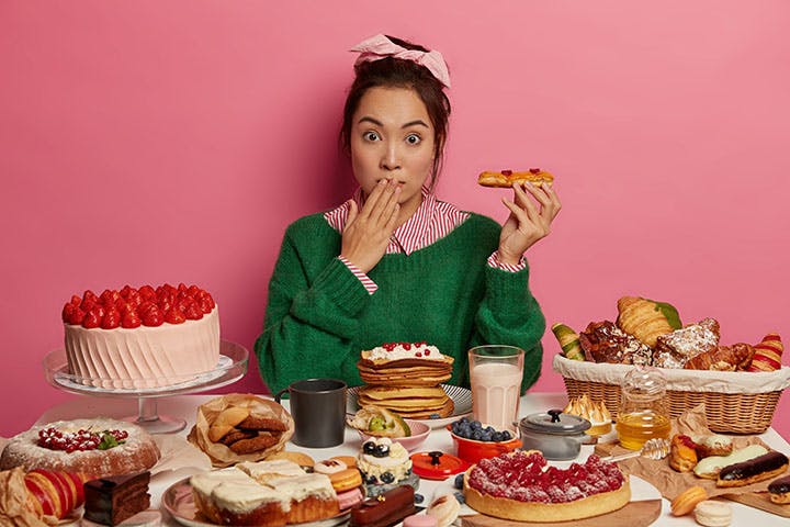 Woman surrounded by sweet, rich, and fatty foods
