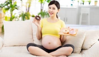 Pregnant woman with a plate of doughnuts in hand