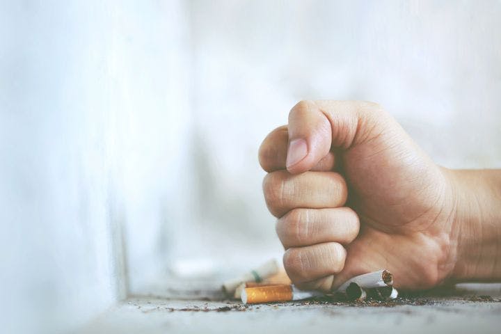 A man using his fist to crush cigarettes