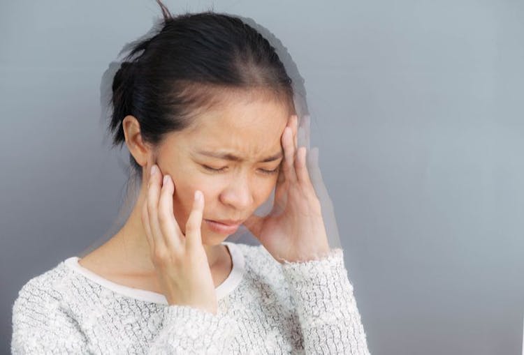 Woman holding her face while grimacing as she experiences dizziness