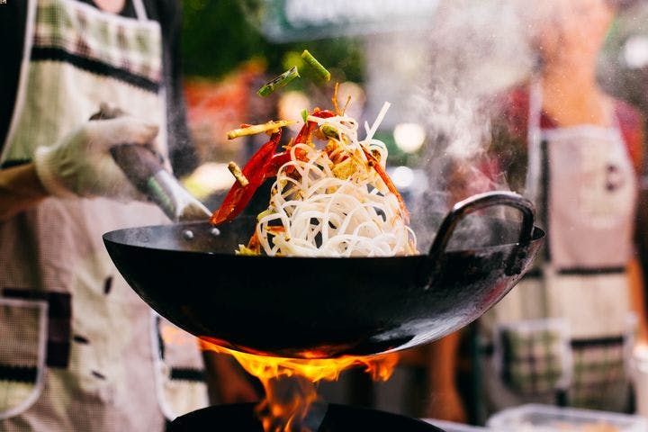 A chef swirling food around in a Chinese wok