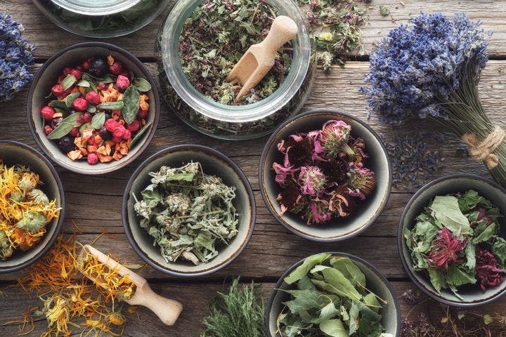 Bowls and jars of medicinal herbs placed on a wooden table 