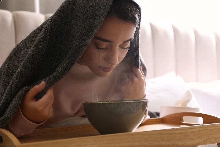 Woman inhaling steam from a bowl of hot water