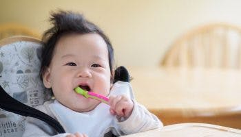 Asian baby with a spoon in mouth