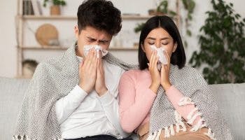 Asian couple having a cold and blowing nose in a paper tissue