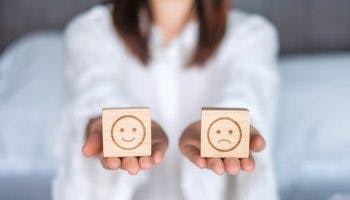 Woman holding smile and angry emotion face blocks.