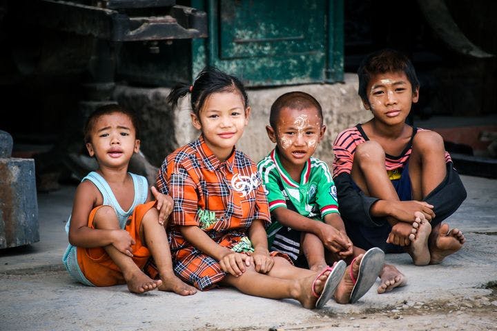 Young Asian children sitting by the roadside.