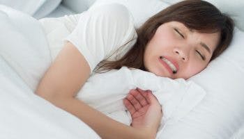 Woman grinding her teeth while sleeping in bed