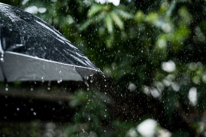 Droplets of rain falling on a black umbrella outdoors