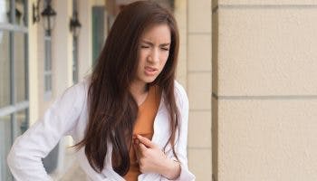 Woman looking uncomfortable while her chest with her left hand
