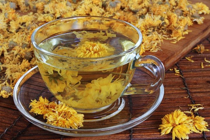 Dried chrysanthemum flowers in a tea cup and on a table