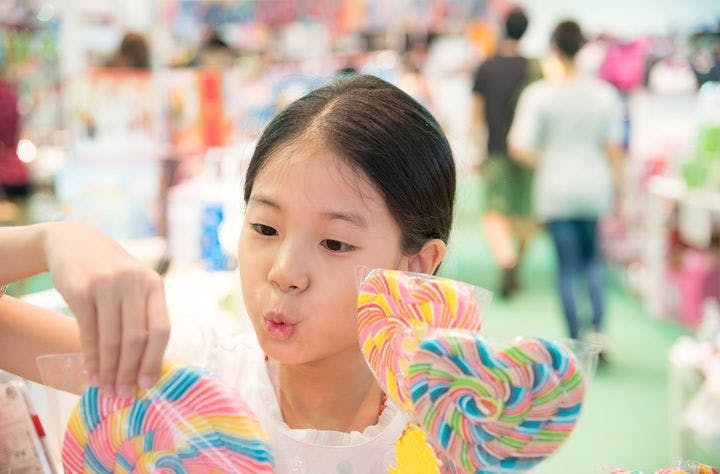 A young girl happily picking out colourful lollipops